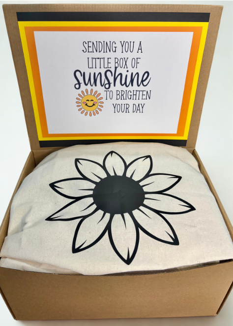 Box with a sunflower design and a card inside, labeled 'Sending you a little box of sunshine to brighten your day'.