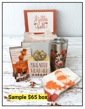 Autumn-themed gift box with 'hello fall' card, tumbler, and pumpkin-themed items on a wooden surface.
