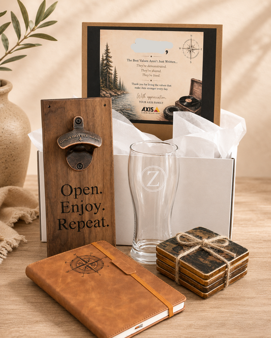 A curated gift set on a wooden tabletop featuring a personalized framed letter to 'ZAC', a wooden bottle opener engraved with 'Open. Enjoy.