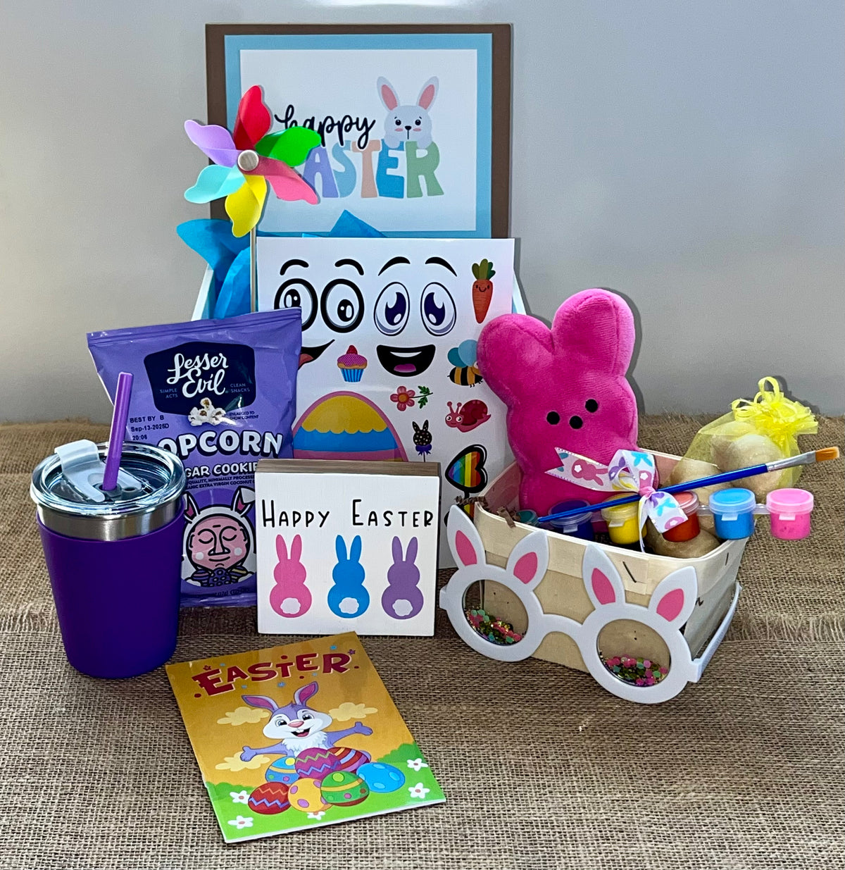 A collection of Easter-themed items including a bunny-themed popcorn bucket, chocolate eggs, a framed 'Happy Easter' sign, and other assorted Easter treats.