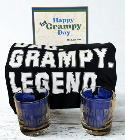 Black t-shirt with 'GRAMPY. LEGEND' text, two shot glasses with 'GRAMPY JUICE' text, and a card reading 'Happy 1st Grampy Day'.