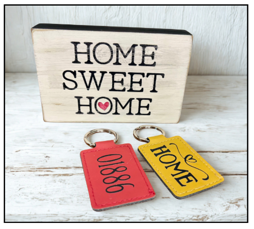 Wooden block with 'Home Sweet Home' text, red keychain with numbers, and yellow keychain with 'Home' text on a wooden surface.
