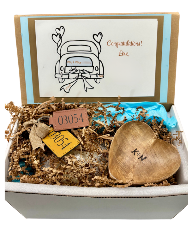 Gift box with a gold heart-shaped object, card, and decorative elements.