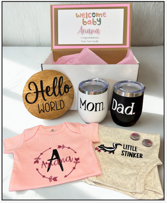 Baby gift set with tumbler, coaster, and baby clothes on a white surface
