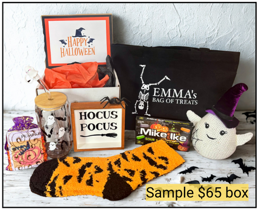 Halloween-themed gift box with various items including a black bag, candy, and a plush toy on a white surface.