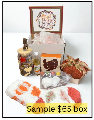 Gift box with various items including a jar, towel, and decorative pumpkins on a white background.