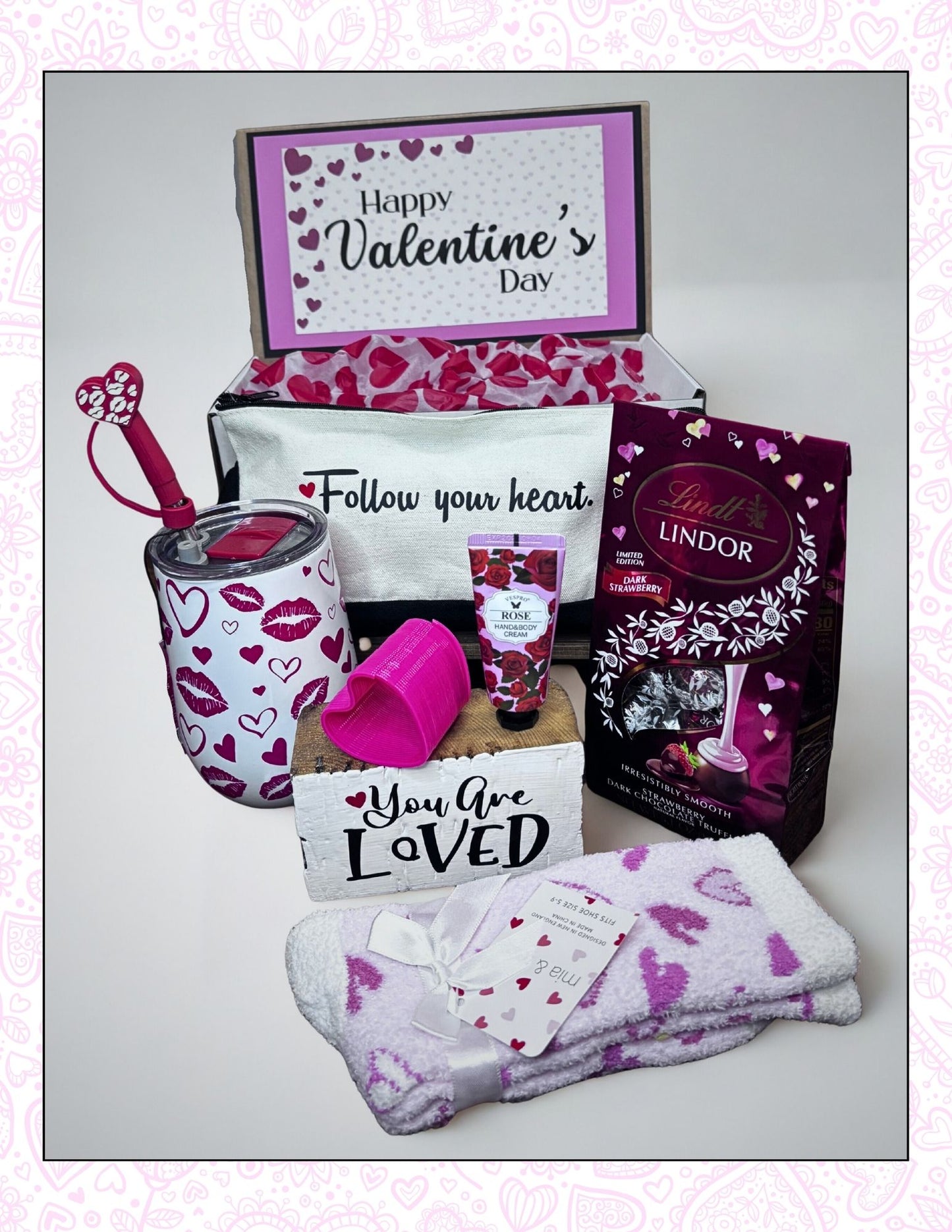 Valentine's Day gift set with Lindt chocolate, mug, and other items on a light background