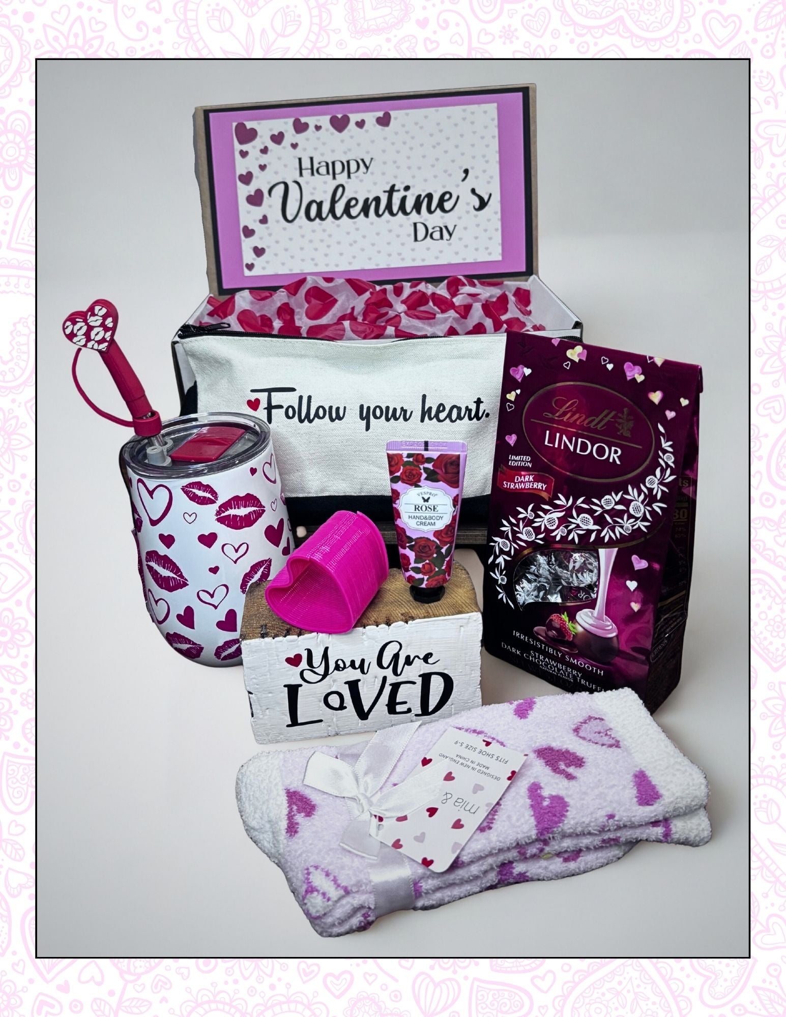 Valentine's Day gift set with Lindt chocolate, mug, and other items on a light background